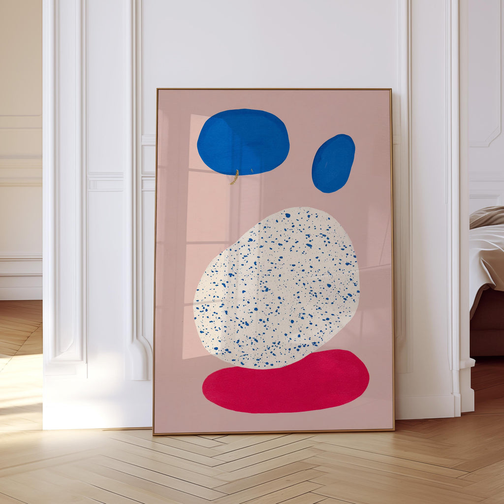 May include: Abstract art print featuring a pink background with blue and red organic shapes. The largest shape is white with blue speckles. The artwork is framed in a thin, brown frame.