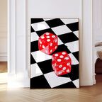 May include: A framed art print featuring two red dice with white dots on a black and white checkered background. The dice are positioned at an angle, creating a dynamic composition. The artwork is displayed in a room with white walls and a wooden floor.