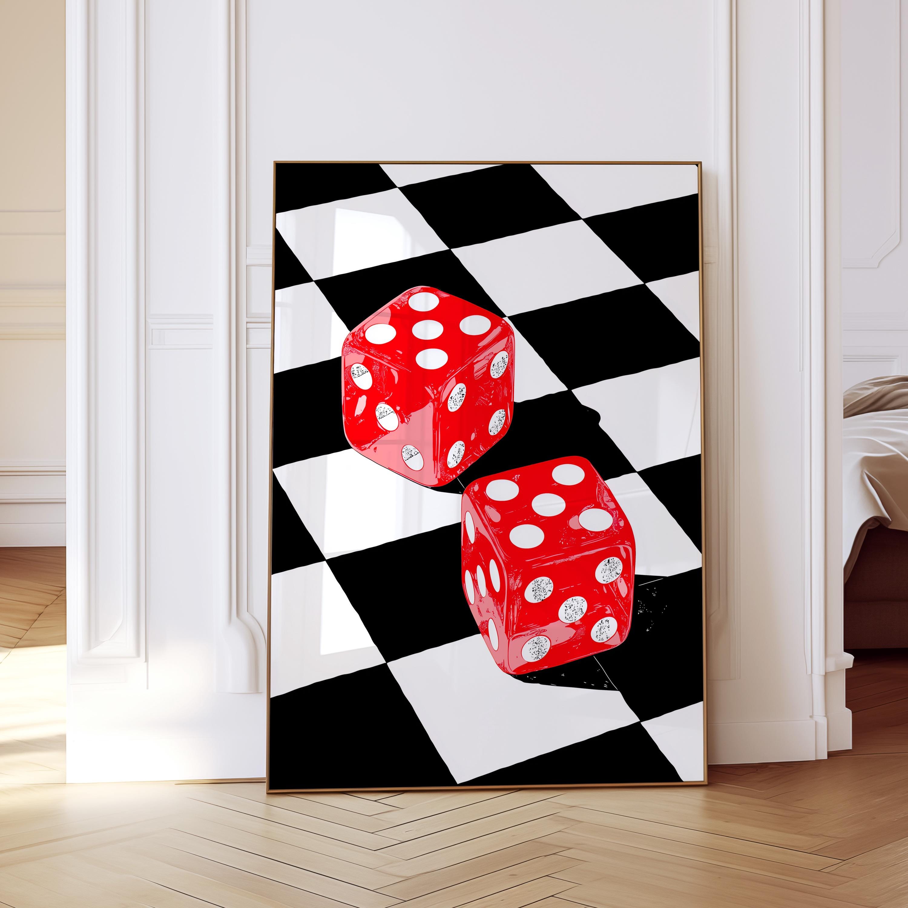 May include: A framed art print featuring two red dice with white dots on a black and white checkered background. The dice are positioned at an angle, creating a dynamic composition. The artwork is displayed in a room with white walls and a wooden floor.