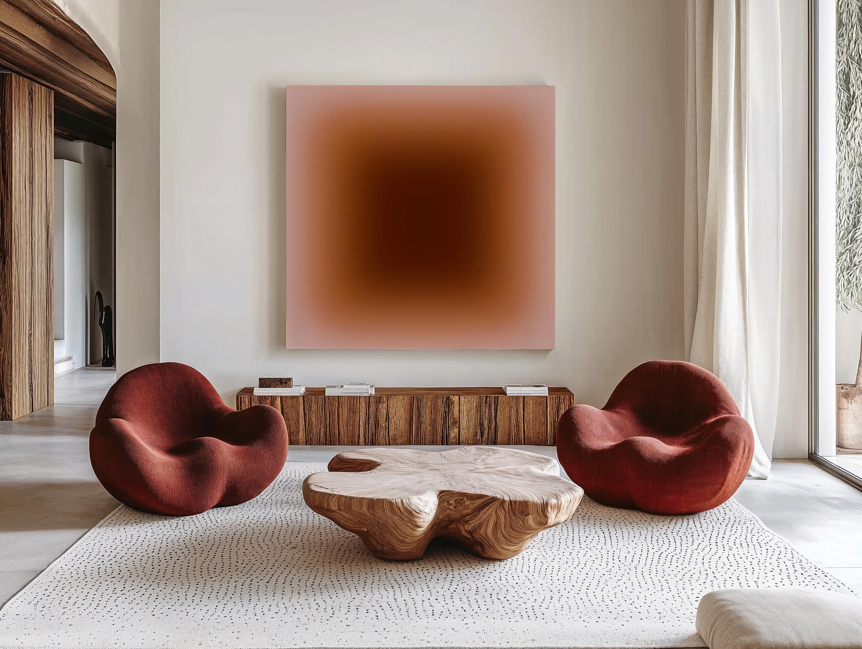 May include: A modern living room featuring two red, rounded armchairs and a unique wooden coffee table. A large, square artwork with a gradient of brown and pink tones hangs above a wooden cabinet. The room has a neutral color palette.