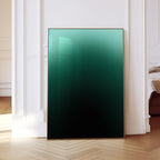May include: A framed art print featuring a gradient of green to black. The artwork is displayed in a gold frame and leans against a white wall and wooden floor. The gradient art piece adds a modern touch to any room.