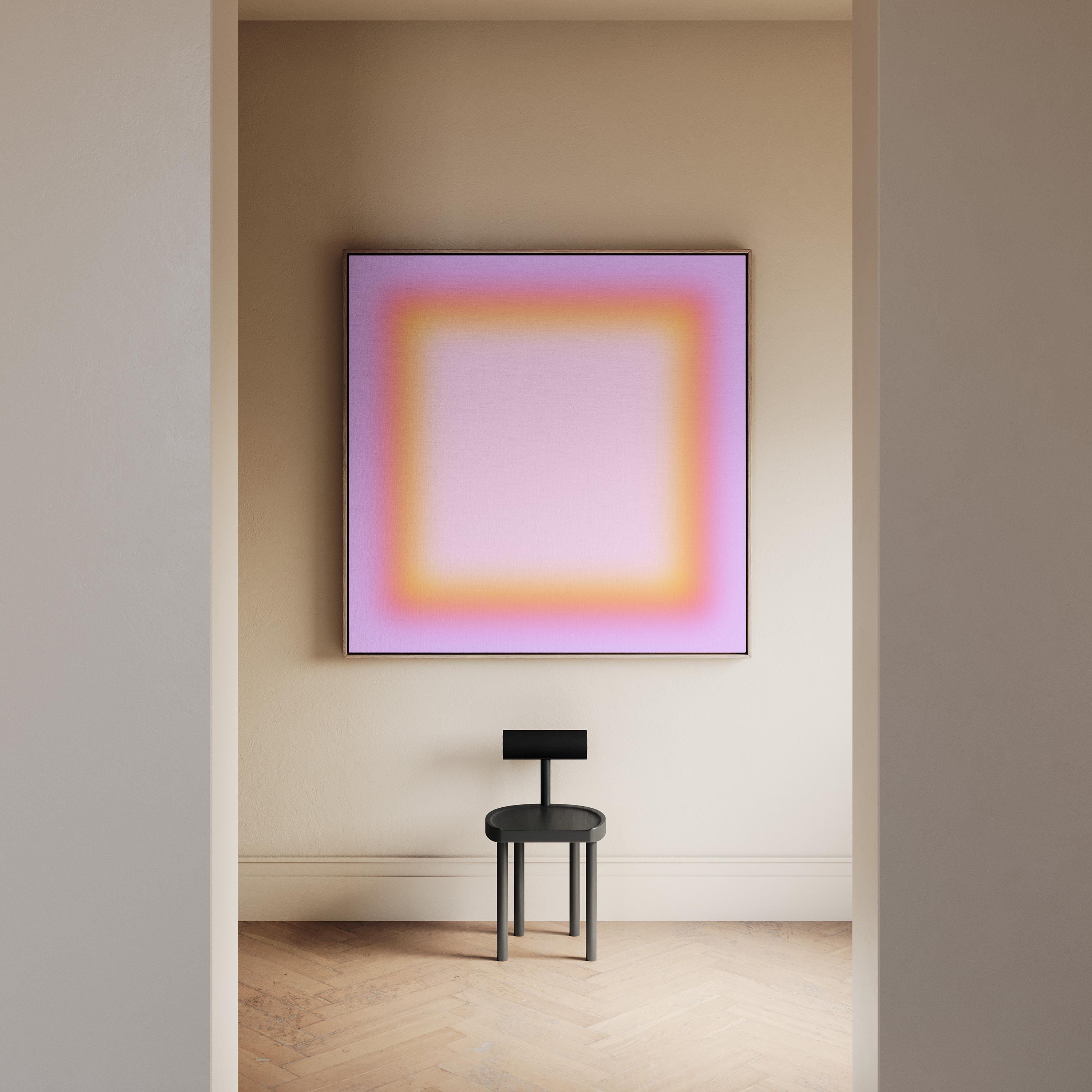 May include: A modern interior scene featuring a framed abstract artwork with a gradient of pink, orange, and yellow hues. Below the artwork, a small black chair with a circular seat and a rectangular backrest is positioned on a light-colored wooden floor.