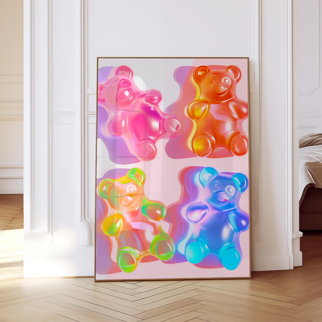 May include: A framed art print featuring four colorful gummy bear illustrations. The bears are in shades of pink, orange, yellow, and blue, with a glossy, translucent appearance. The artwork is displayed in a gold frame, leaning against a white wall.