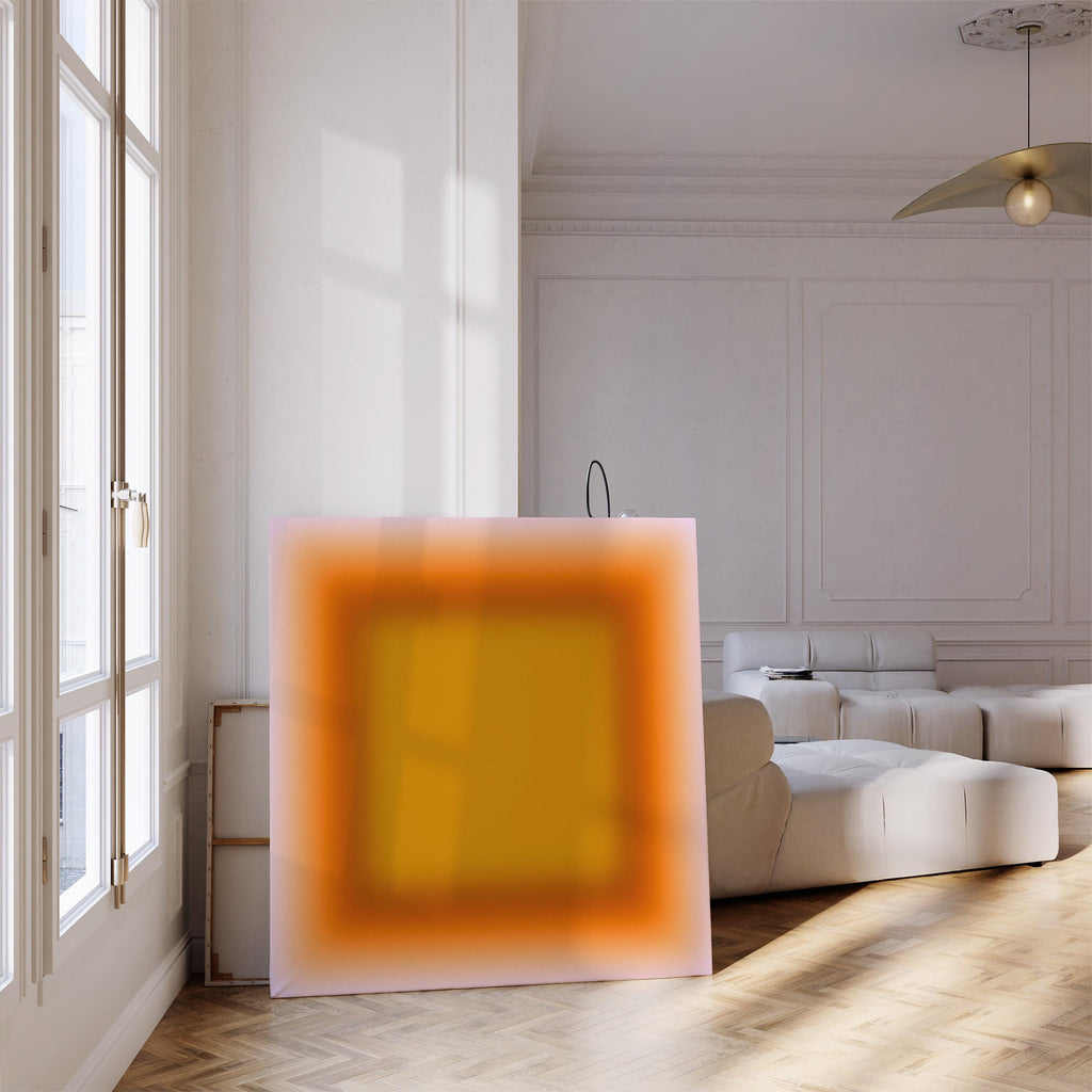 May include: A large, square canvas with an abstract design. The artwork features a gradient of colors, with a central yellow square framed by orange and a soft pink outer edge. The piece is leaning against a wall in a well-lit room.
