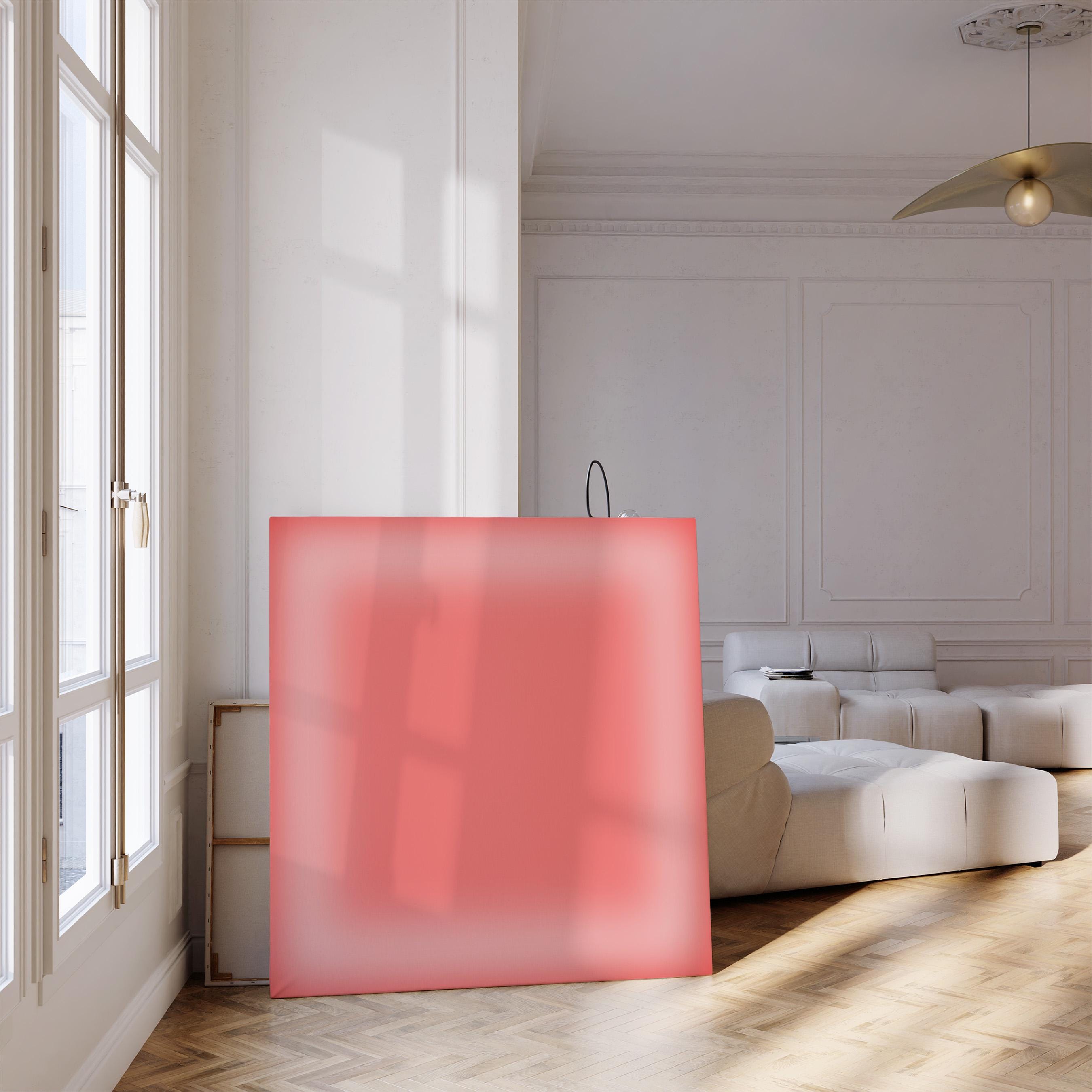 May include: A large, square, coral-colored canvas leans against a wall in a bright, modern room. The canvas has a soft, diffused gradient effect. The room features a white sofa, a large window, and a wooden floor.