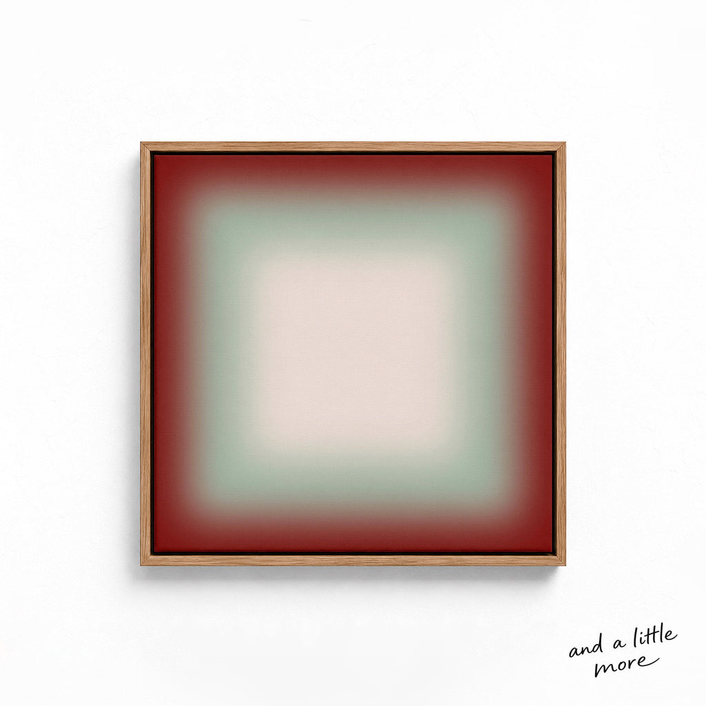 A square, abstract artwork with a gradient background transitioning from red to green. The artwork is framed in a wooden frame and is displayed on a white wall.