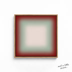 A square, abstract artwork with a gradient background transitioning from red to green. The artwork is framed in a wooden frame and is displayed on a white wall.
