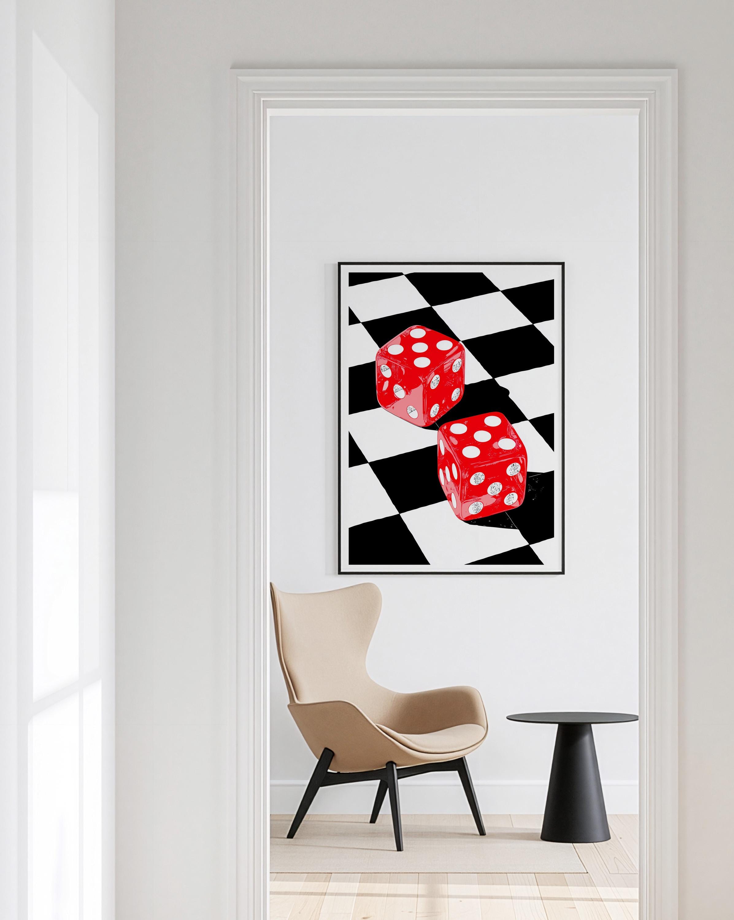 May include: A framed art print featuring two red dice with white dots against a black and white checkered background. The dice are the focal point, with a modern, graphic style. The artwork is displayed in a room with a chair and side table.