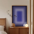 May include: A modern bedroom scene featuring a wooden cabinet with a framed abstract art piece in shades of blue. A beige vase with a plant and a spherical lamp sit on the cabinet. A bed with a woven headboard is partially visible.