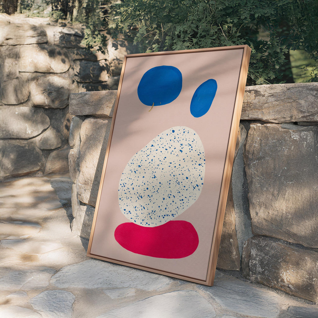 May include: Abstract art print featuring a light pink background with blue and red organic shapes. The largest shape is white with blue speckles. The artwork is framed in a natural wood frame.