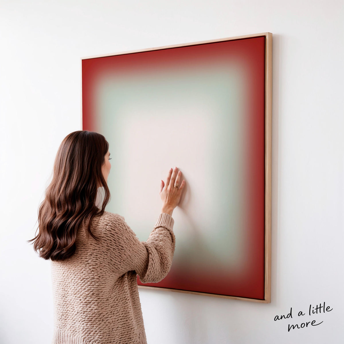 A woman in a brown sweater is standing in front of a large abstract painting, touching the frame of the artwork.