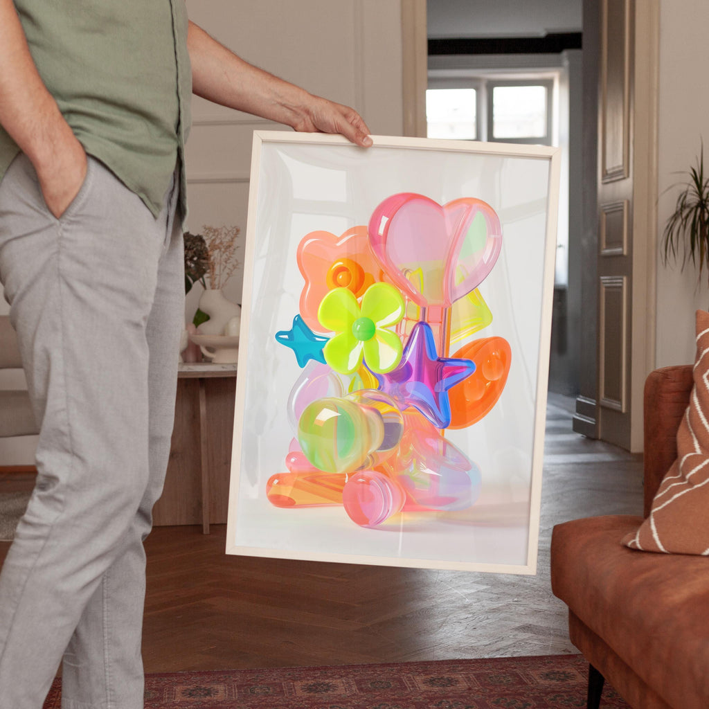 May include: A framed artwork featuring a vibrant arrangement of translucent, colorful shapes. The composition includes a heart, flowers, stars, and other abstract forms in shades of pink, orange, green, and blue. The artwork is held by a person.