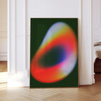 May include: A framed abstract art print featuring a vibrant, blurred design. The artwork showcases a gradient of colors, including red, orange, yellow, and blue, set against a dark green background. The print is displayed in a room with white walls and a wooden floor.