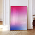 May include: A framed artwork with a gradient of pink, purple, and blue hues. The artwork is displayed against a white wall and a light-colored wooden floor. The frame is a warm brown color.