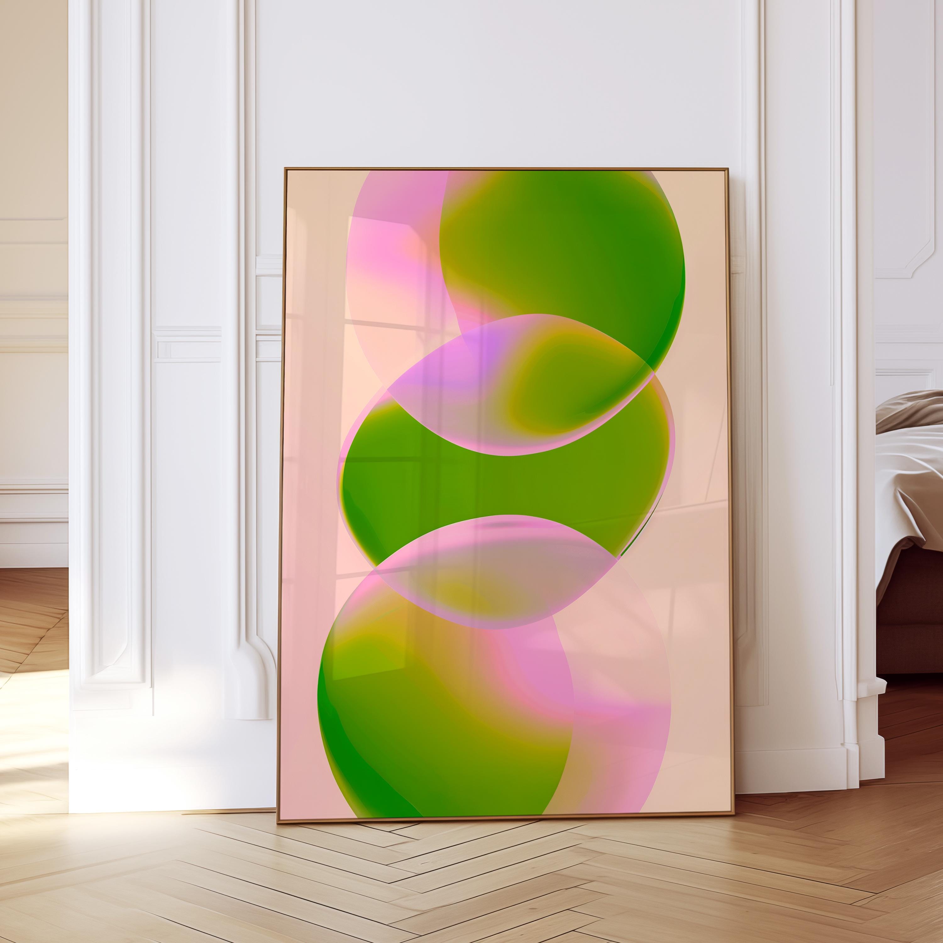 May include: Abstract art print featuring overlapping, translucent orbs in shades of green and pink against a light peach background. The artwork is framed in a thin, gold-colored frame and leans against a white wall.
