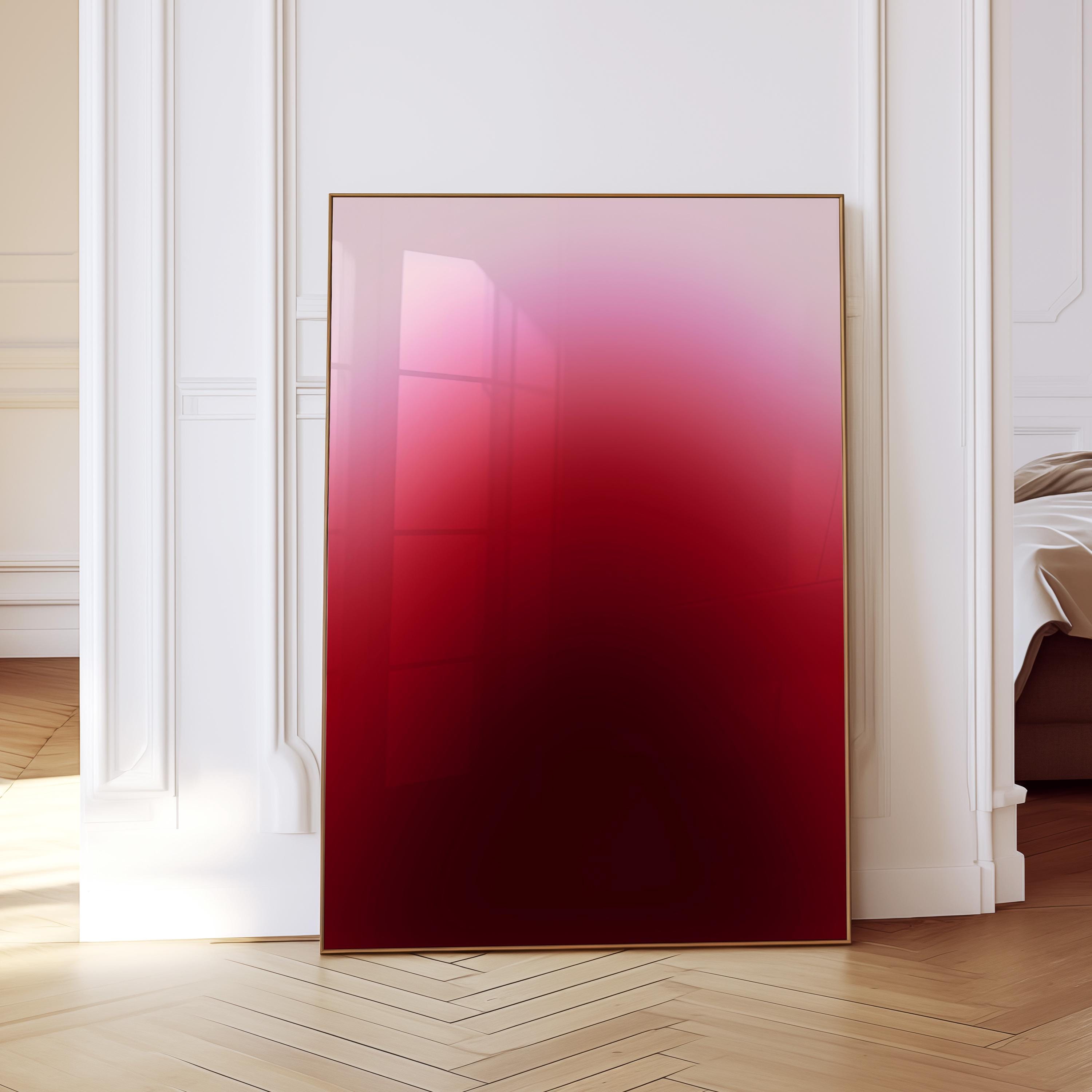 May include: A framed artwork with a gradient of colors from light pink to deep red. The artwork is displayed in a room with white trim and a wooden floor. The frame is a thin, gold color.