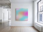 May include: Square canvas art with a soft, blurred gradient of colors including pink, orange, blue, and yellow. The text "everything comes down my side" is written in white script. The artwork hangs on a white wall in a bright room.