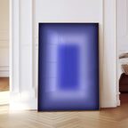 May include: A framed abstract art piece with a gradient of blue hues. The artwork is rectangular, with a dark blue border and a lighter blue center. The piece is displayed against a white wall and a light wood floor.