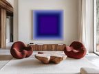 May include: A modern living room featuring a large abstract painting with a gradient of blue and purple hues. Two rounded, rust-colored chairs face a unique wooden coffee table. A wooden cabinet and a patterned rug complete the contemporary design.